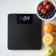 Eine Waage und frische Früchte, symbolisiert Gewichtsmanagement.